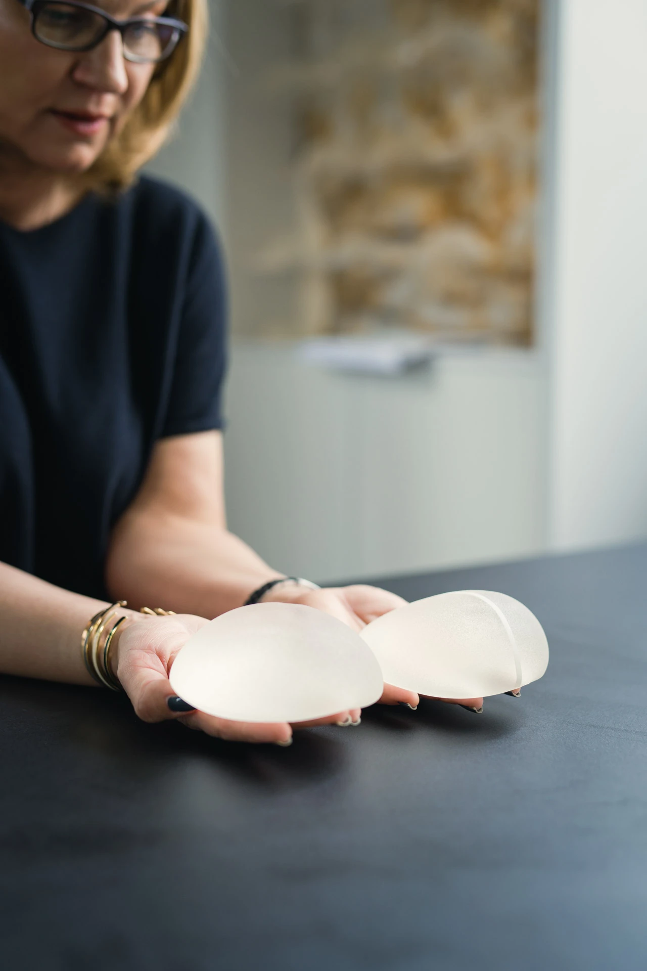 Frau mit Implantate in Händen, Fokus auf Implantaten